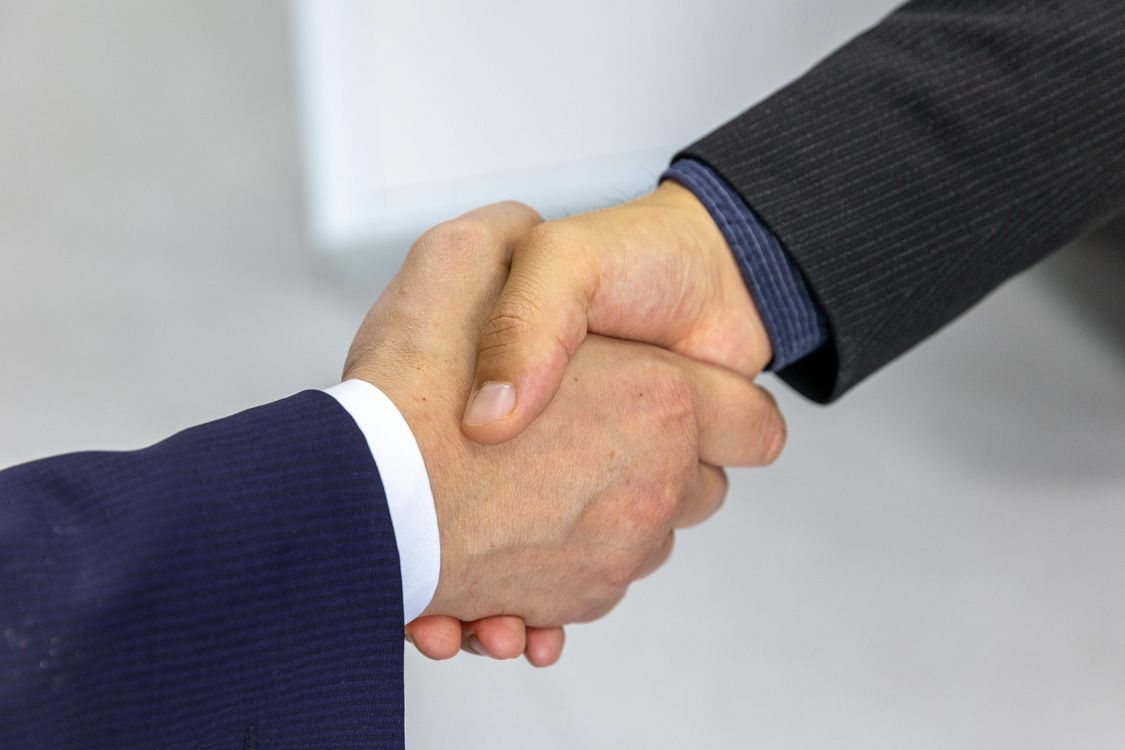 Zwei Geschäftsleute im Anzug geben sich die Hand — Symbol für die Zusammenarbeit von Unternehmen und Personalberatung