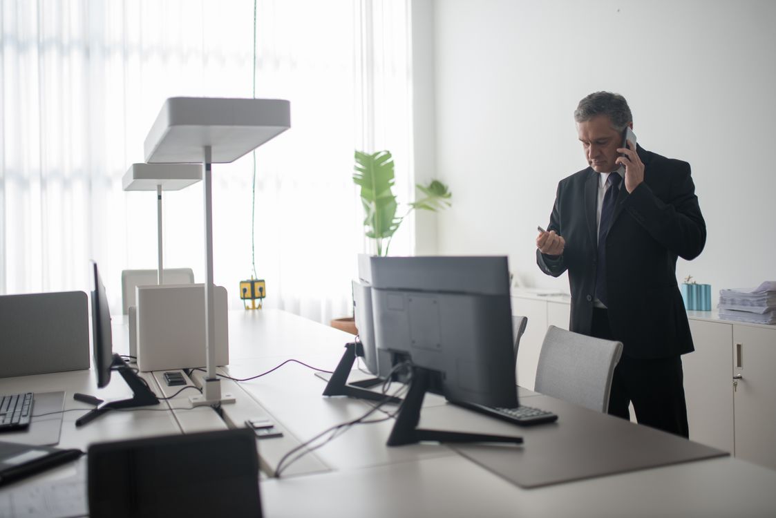 Erfahrener Manager im Anzug telefoniert in einem modernen Büro während eines Interim-Mandats