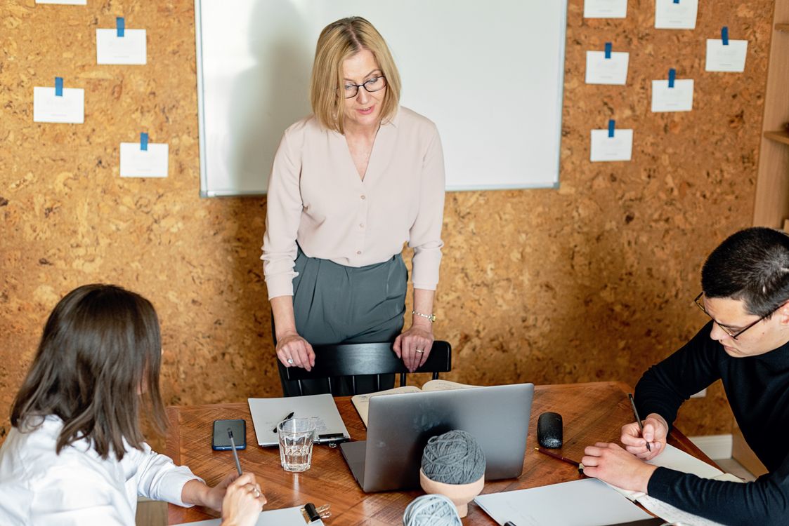 Geschäftsführerin bespricht mit zwei Mitarbeitenden die Positionierung des Unternehmens im Besprechungsraum