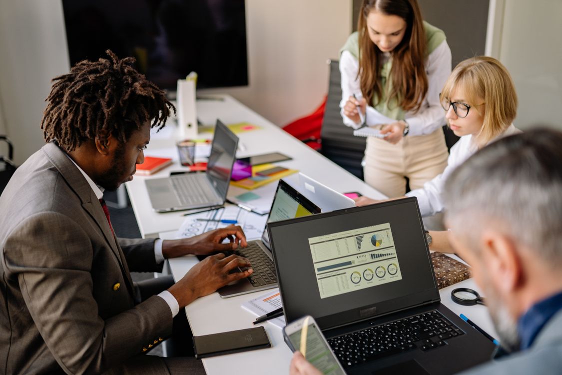 Projektteam wertet im Büro Kennzahlen eines Digitalisierungsprojekts an Laptops aus