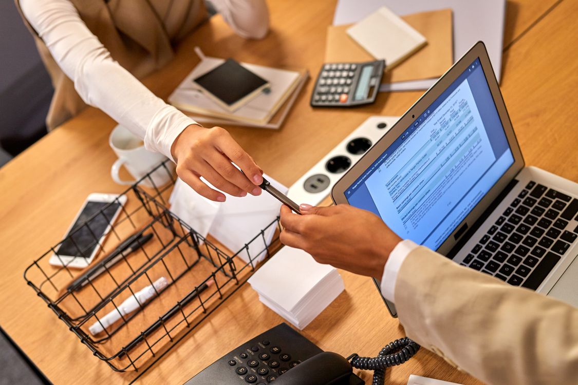 Zwei Mitarbeitende füllen am Schreibtisch mit Laptop und Taschenrechner den Förderantrag für eine Unternehmensberatung aus