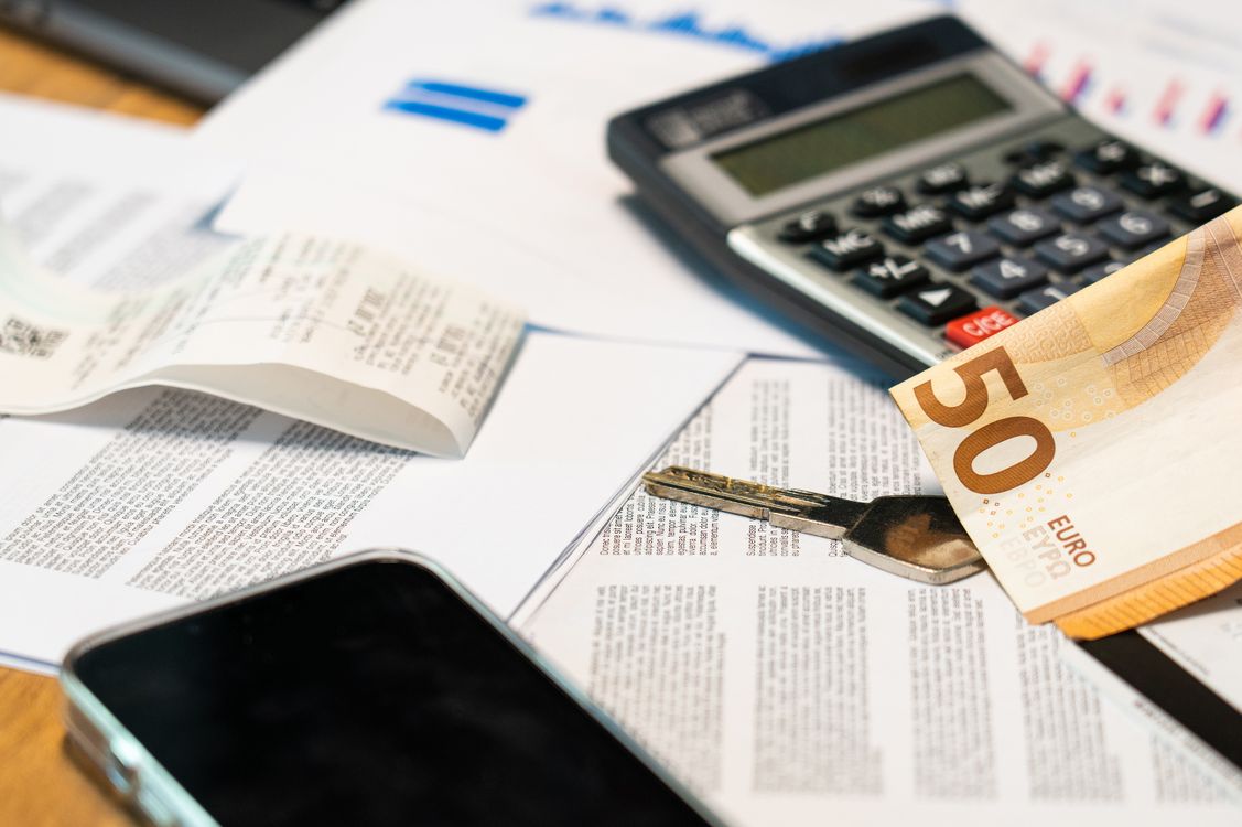 Finanzunterlagen, Taschenrechner und Geldschein auf dem Schreibtisch der kaufmännischen Leitung