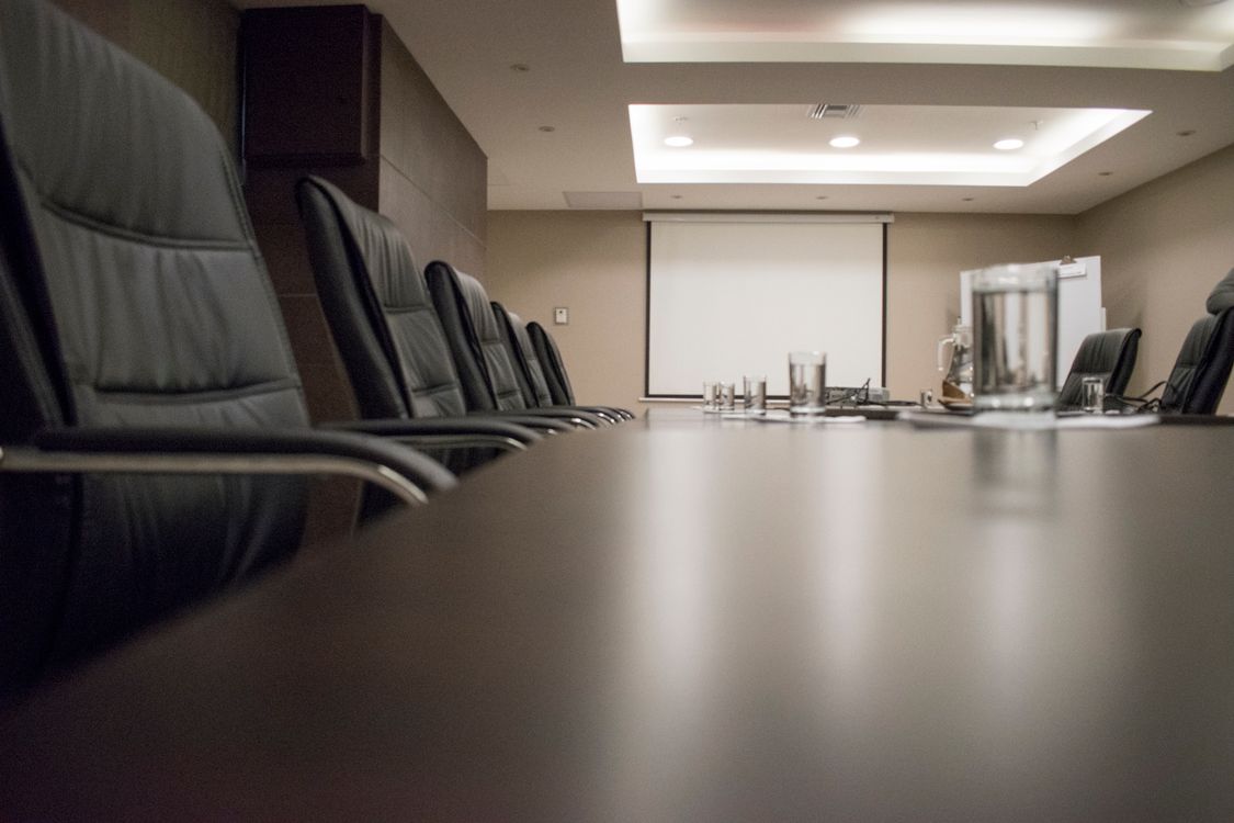 Leerer Konferenztisch mit unbesetzten Stühlen als Sinnbild für eine offene Führungsposition