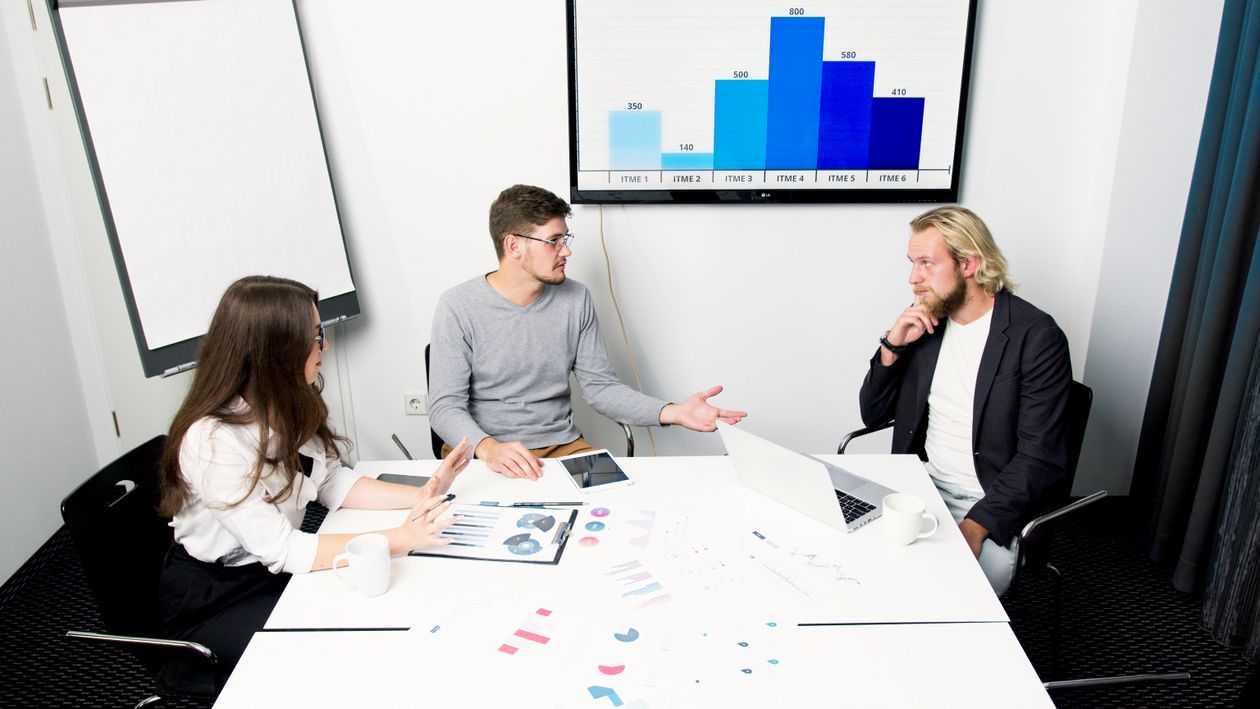 Vertriebsteam analysiert im Besprechungsraum die Umsatzzahlen auf einem Balkendiagramm
