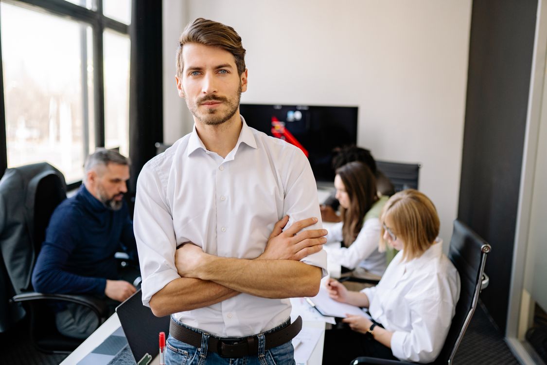 Interim Manager steht im Büro vor seinem Team und übernimmt befristet die Führung eines Bereichs