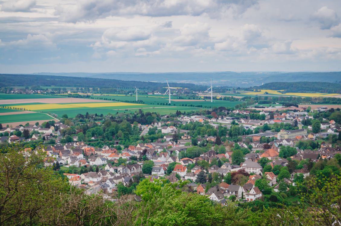 Blick über eine Kleinstadt mit Gewerbegebiet, Feldern und Windrädern, typischer Mittelstandsstandort abseits der Großstadt