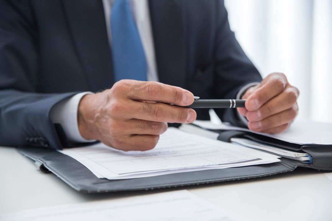 Führungskraft hält vor dem Unterschreiben des Arbeitsvertrags zögernd den Stift in der Hand