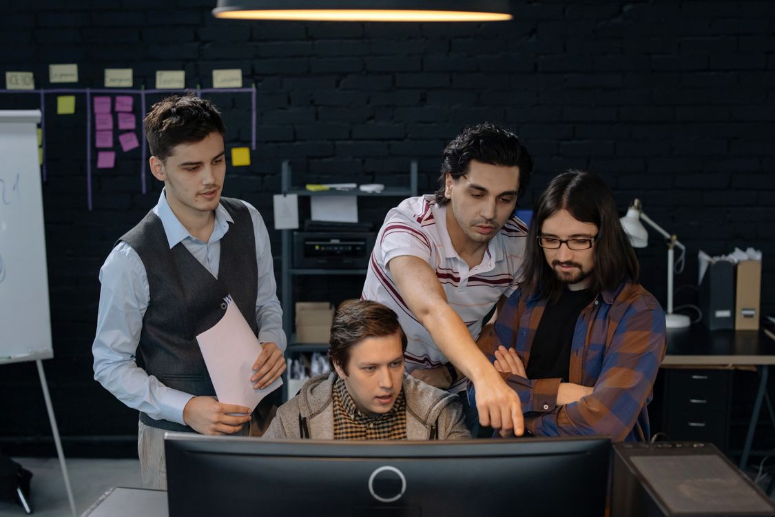 Entwicklungsteam in einem Softwarehaus bespricht mit seiner Teamleitung Code am Bildschirm