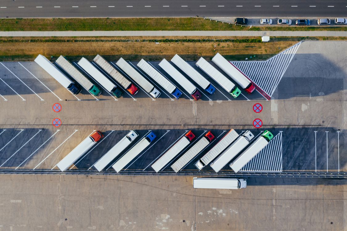 Luftaufnahme eines Logistikhofs mit parkenden Sattelzügen in geordneten Reihen