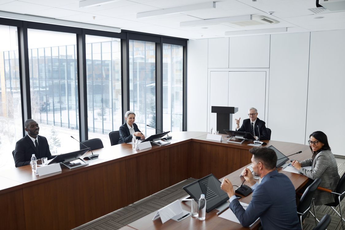 Führungskräfte zweier Unternehmen sitzen sich nach einer Übernahme im Konferenzraum gegenüber und besprechen die neue Führungsstruktur