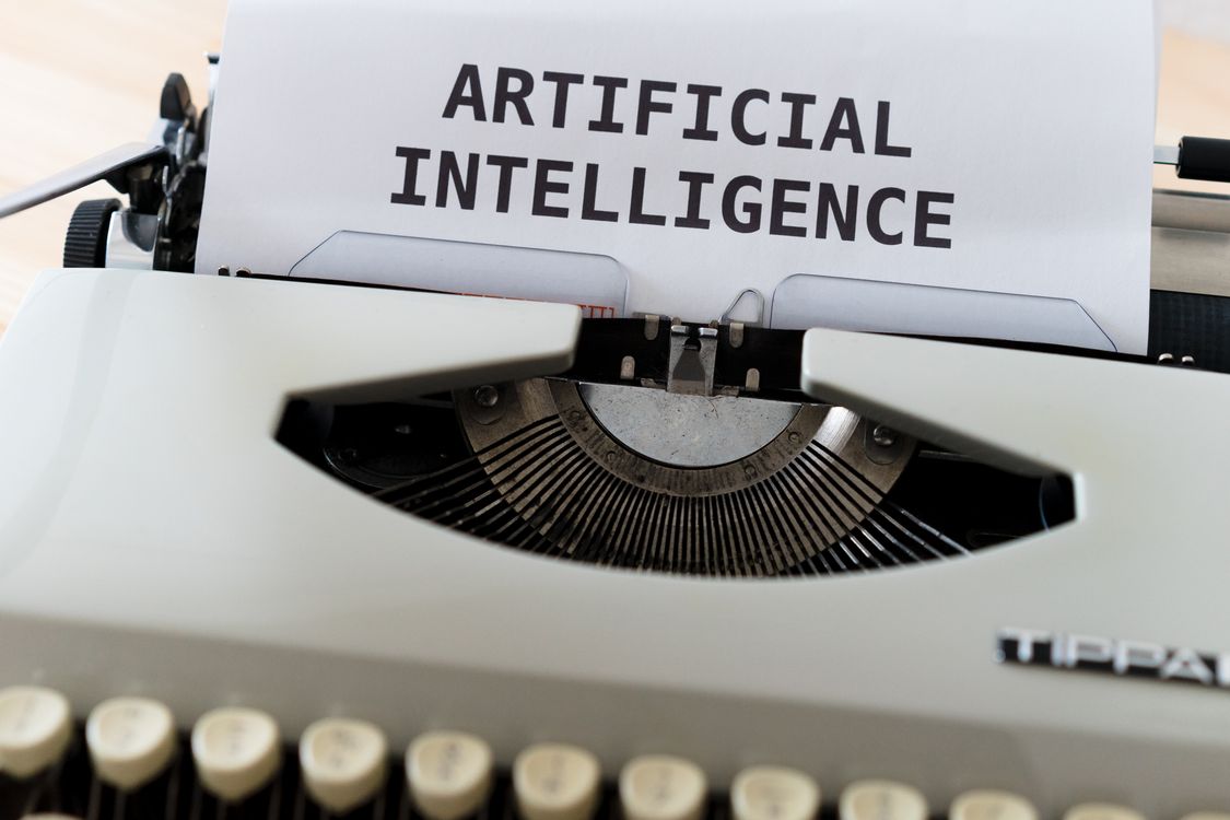 Schreibmaschine mit dem Schriftzug Artificial Intelligence auf einem Blatt Papier