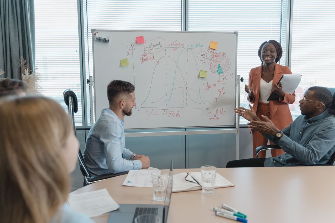 Team im Besprechungsraum diskutiert ein Diagramm auf einem Whiteboard