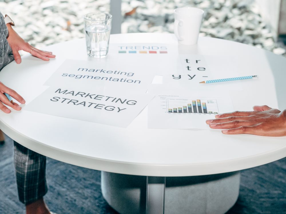 Zwei Personen besprechen an einem runden Tisch Marketingstrategie, Segmentierung und Auswertungen